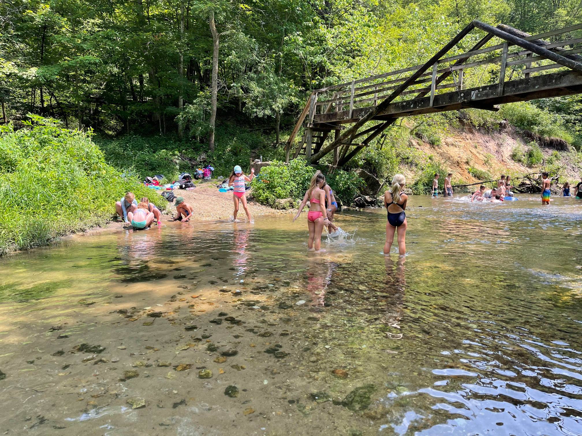 Campers playing in the river underneath the A-Frame Bridge.