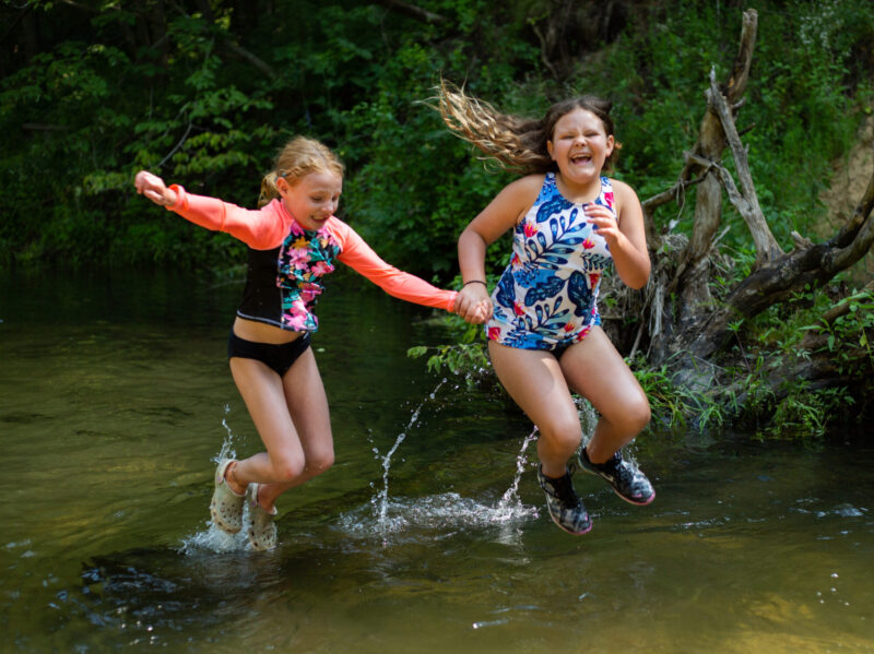 2 girls jumping into the river